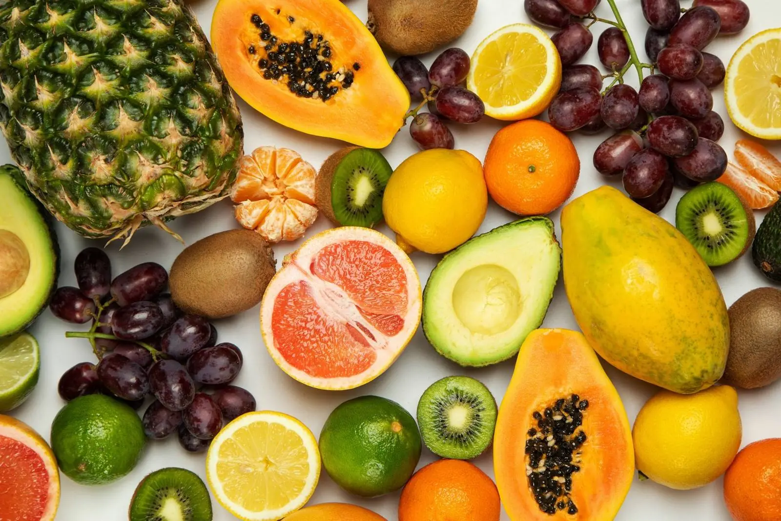 Halved tropical fruits: papaya, pineapple, citrus and avocado